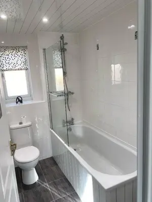 a white bathroom with a tub and a toilet at Millview house in Airdrie