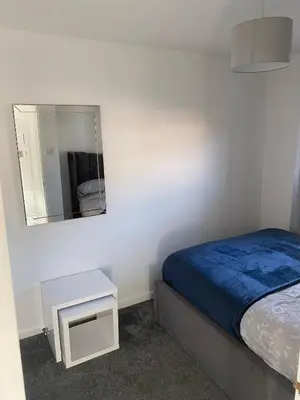 a small bedroom with a bed and a mirror at Millview house in Airdrie