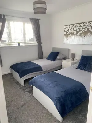 a bedroom with two beds with blue sheets at Millview house in Airdrie