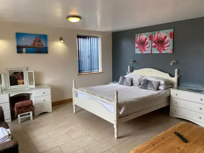 a bedroom with a white bed and a dresser at Folly gardens in Moffat