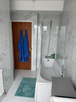 a bathroom with a tub and a shower and a wooden door at Your Base To Explore London in Moffat