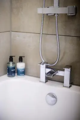 a bathroom sink with a faucet and two bottles of soap at Cuan Flat - Oban in Oban