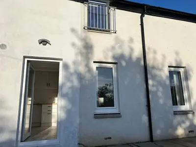 a white building with a door and a window at Self-contained ground level cottage with hill view in Edinburgh