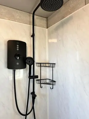 a shower in a bathroom with two shelves at Self-contained ground level cottage with hill view in Edinburgh