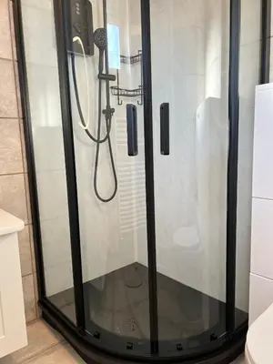 a shower with a glass door in a bathroom at Self-contained ground level cottage with hill view in Edinburgh