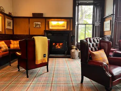 a living room with two chairs and a fireplace at Kilfinan Hotel in Kilfinan