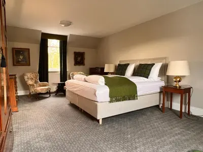 a bedroom with a large bed and a chair at Kilfinan Hotel in Kilfinan
