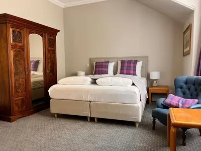 a bedroom with a bed and a blue chair at Kilfinan Hotel in Kilfinan