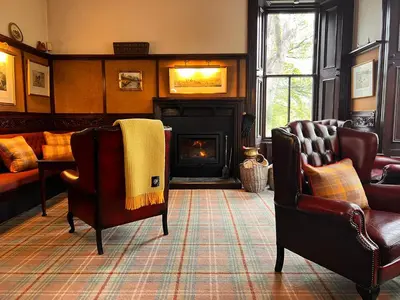 a living room with two chairs and a fireplace at Kilfinan Hotel in Kilfinan