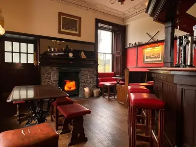 a bar with a fireplace and some chairs and a table at Kilfinan Hotel in Kilfinan