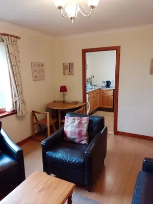 a living room with a leather couch and a table at Lochside Cottage Glencoe
