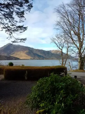 a bench with a view of a lake and mountains at Lochside Cottage Glencoe