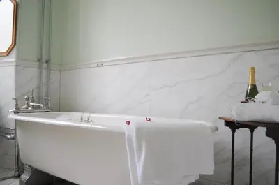 a white bath tub in a bathroom with a bottle of champagne at The South Wing in Acharn