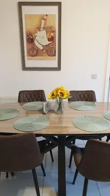 a wooden table with chairs and a picture on the wall at Entire Spacious 3-Bed Family Home, City Centre, Free Parking, Garden in Glasgow