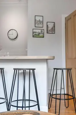 a kitchen with three bar stools and a clock on the wall at GuestReady - Modern 1BR in Edinburgh in Edinburgh