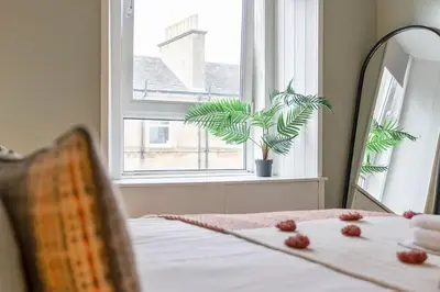 a bedroom with a bed with a plant in a window at GuestReady - Modern 1BR in Edinburgh in Edinburgh
