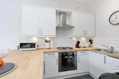 a kitchen with white cabinets and a stove top oven at GuestReady - Modern 1BR in Edinburgh in Edinburgh