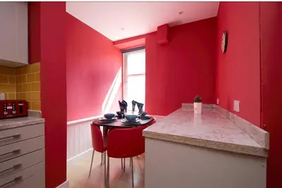 a red kitchen with a counter and red walls at Edinburgh Drumdryan Central Apart in Edinburgh
