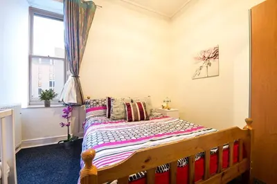 a bedroom with a wooden bed with a window at Edinburgh Central Morrison Apartment in Edinburgh