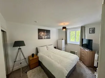 a bedroom with a white bed and a television at Superb Homestay in Cowlairs