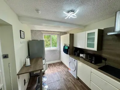 a kitchen with a refrigerator and a washer at Superb Homestay in Cowlairs