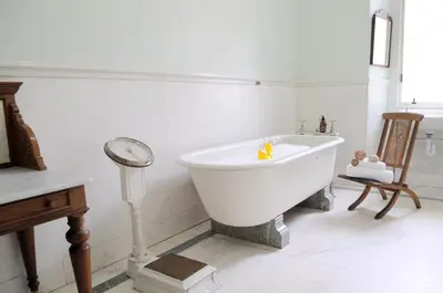 a white bath tub in a room with a clock at The Billiard Room Flat