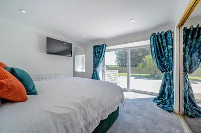 a bedroom with a bed with blue curtains and a window at 3 Bed in Leswalt oc-g32241 in Leswalt