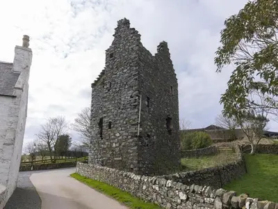 an old stone building next to a stone wall at 3 Bed in Leswalt oc-g32241 in Leswalt