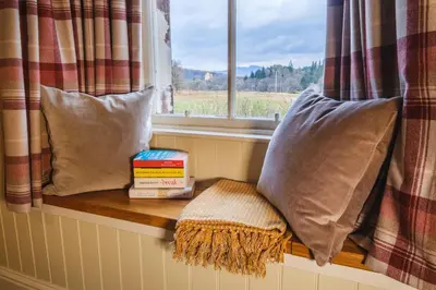 a window sill with two pillows and a book at Craigendarroch No 1 in Acharn