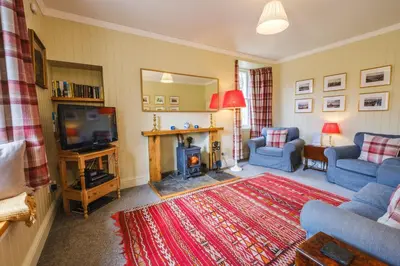 a living room with a fireplace and a tv at Craigendarroch No 1 in Acharn