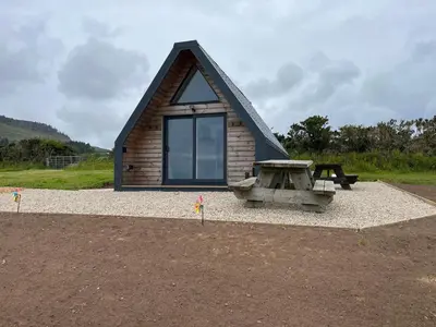 a small log cabin with a picnic table and a picnic table at Tiny home on an organic croft, Isle of Arran in Kildonan