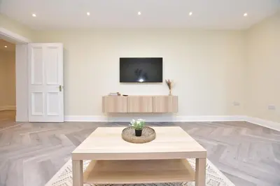 a living room with a table and a tv on a wall at The Cliff Retreat in Wemyss Bay