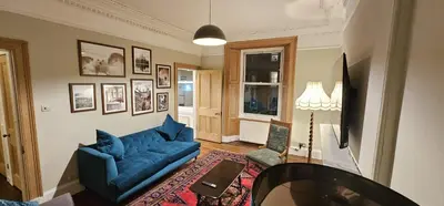 a living room with a blue couch and a table at Cosy 2 bedroom flat-castle view in Edinburgh