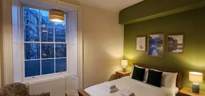 a green bedroom with a bed and a window at Cosy 2 bedroom flat-castle view in Edinburgh