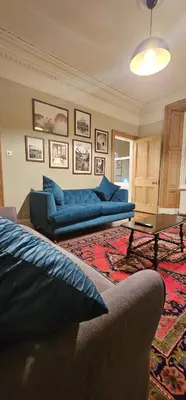 a living room with two blue couches and a table at Cosy 2 bedroom flat-castle view in Edinburgh