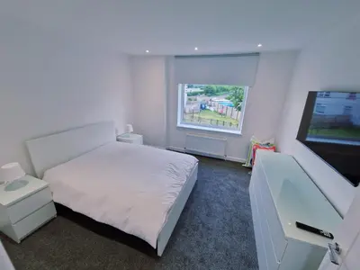 a bedroom with a bed and a flat screen tv at Modern 2 Bedroom with extra Loft Bedroom in Glasgow