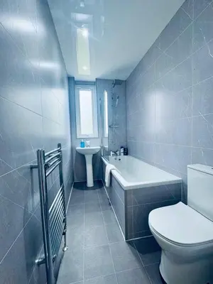 a bathroom with a toilet and a tub and a sink at Modern 2 Bedroom with extra Loft Bedroom in Glasgow