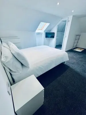 a bedroom with a large white bed with a window at Modern 2 Bedroom with extra Loft Bedroom in Glasgow