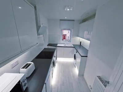 a small kitchen with white cabinets and a sink at Modern 2 Bedroom with extra Loft Bedroom in Glasgow