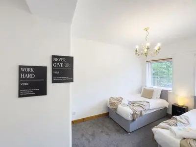 a bedroom with two beds and a chandelier at Clydebank 2 Bedroom Home in Drumchapel
