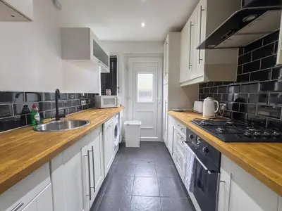 a kitchen with white cabinets and wooden counter tops at Clydebank 2 Bedroom Home in Drumchapel