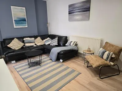 a living room with a black couch and a chair at Central Portrush Townhouse available for Open Golf in Moffat