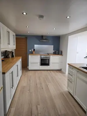 a large kitchen with white cabinets and wooden floors at Central Portrush Townhouse available for Open Golf in Moffat