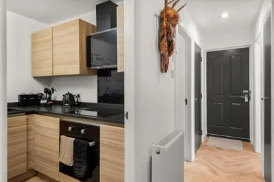 a kitchen with wooden cabinets and a black stove top oven at Ochil View 30 mins to Edinburgh and Glasgow in Falkirk