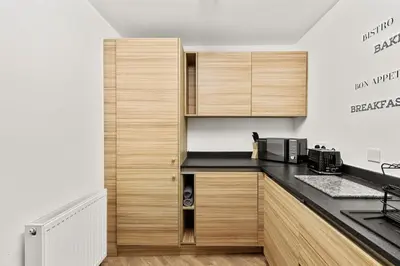 a kitchen with wooden cabinets and a black counter top at Ochil View 30 mins to Edinburgh and Glasgow in Falkirk