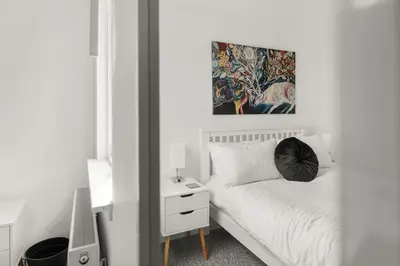 a white bedroom with a bed with a black pillow at Ochil View 30 mins to Edinburgh and Glasgow in Falkirk