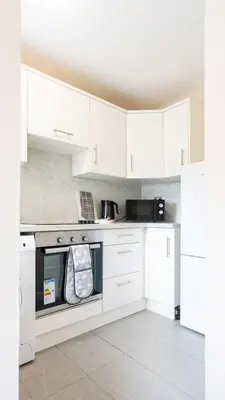 a kitchen with white cabinets and a dishwasher at Forbes House in Glasgow