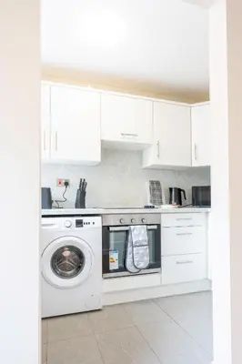 a white kitchen with a washing machine in it at Forbes House in Glasgow