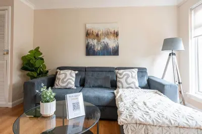 a living room with a blue couch and a glass table at Forbes House in Glasgow