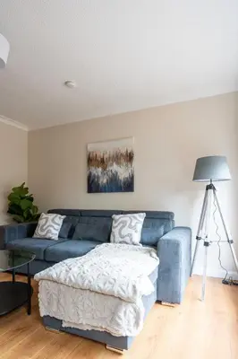 a living room with a blue couch and a table at Forbes House in Glasgow